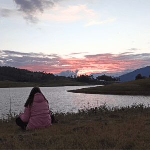 Mujer relajada viendo el atardecer en el lago Calima