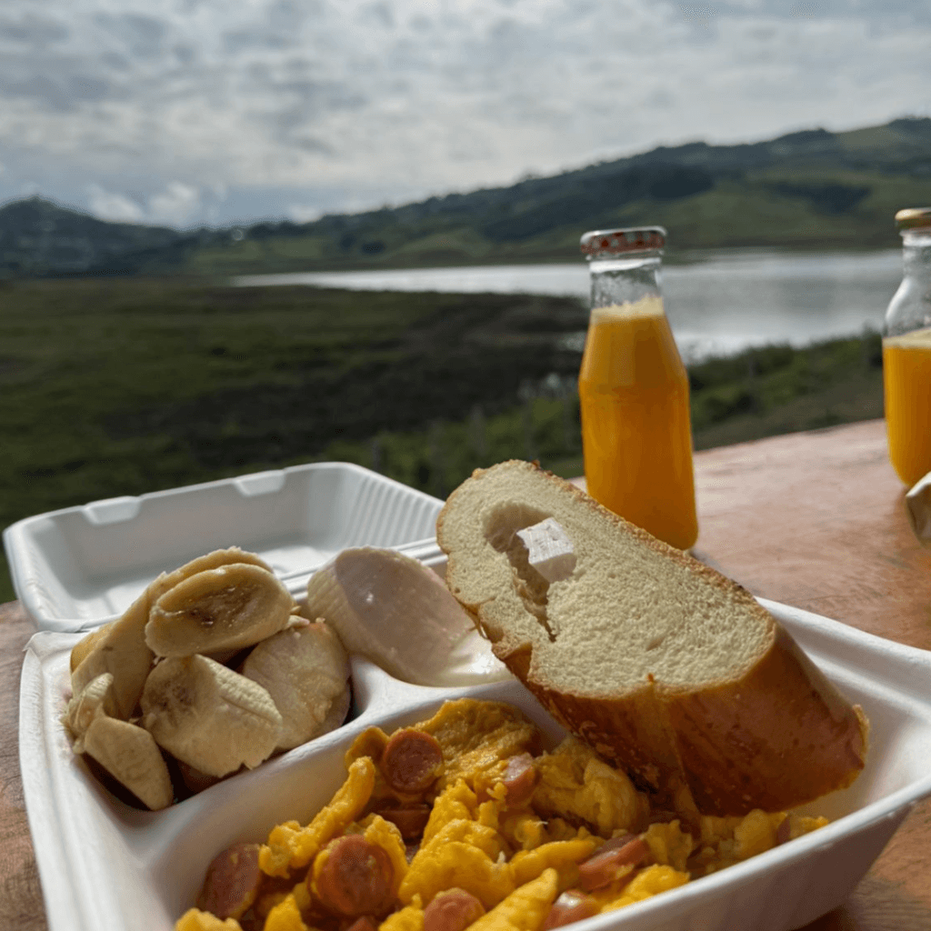 Desayuno artesanal con frutas y café servido al aire libre con vista al lago.